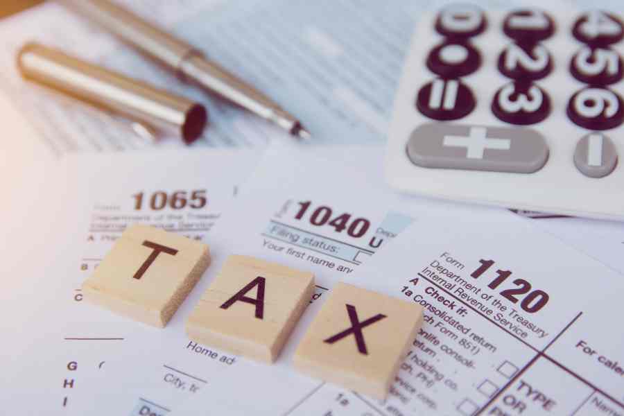 Tax season with wooden alphabet blocks, calculator, pen on 1040 tax form backgrounda.