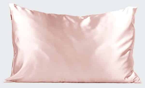 Pink silk pillow case on pillow against light grey background.