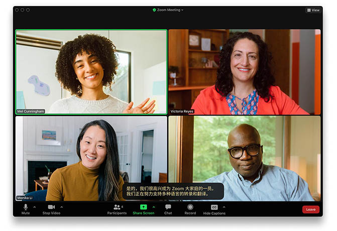 A live Zoom meeting showing four participants' thumbnails and an auto-generated caption