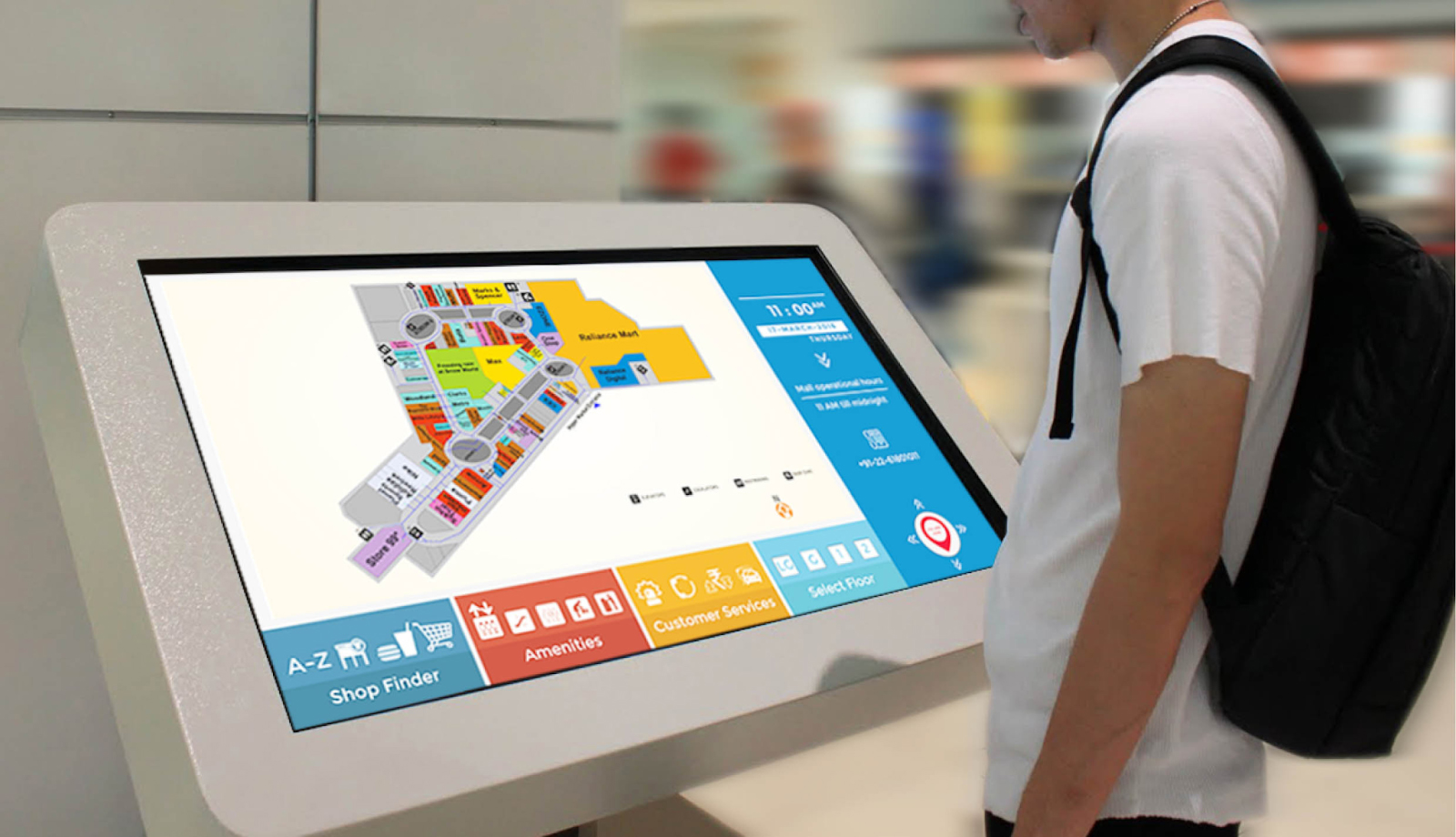 A shopper reviews a mall map on a freestanding digital display.