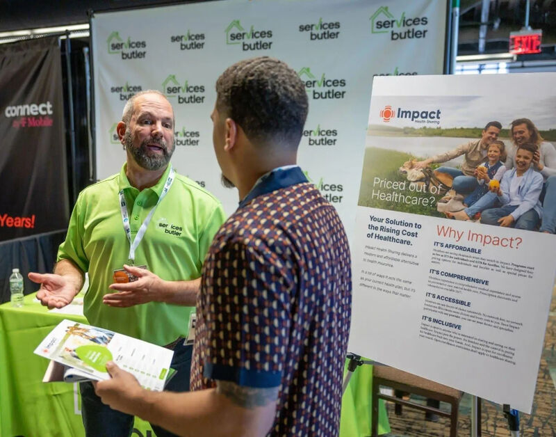 A representative from Services Butler talking to a male attendee at a Small Business Expo booth.