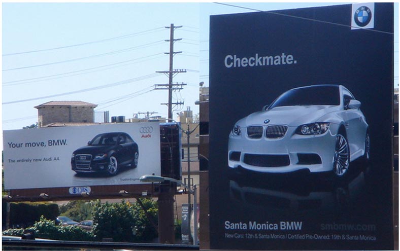 BMW billboard with "Checkmate" slogan next to Audi billboard saying "Your move, BMW"
