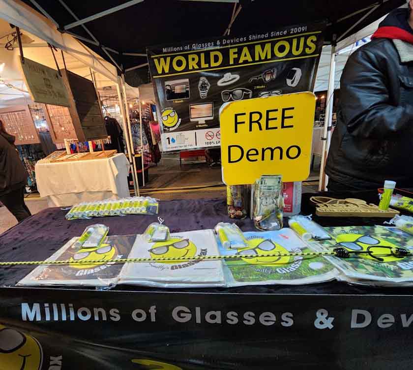 Market seller offering free demo of his eyeglass cleaner along with his branded microfiber cloths.