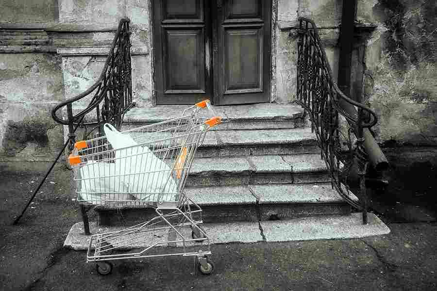 Abandoned shopping cart in front of an abandoned house.