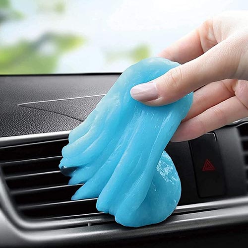 Blue cleaning gel being used to clean car AC vent.