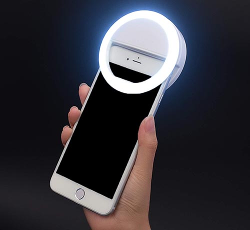 Lit up selfie phone ring light on white iPhone black background.