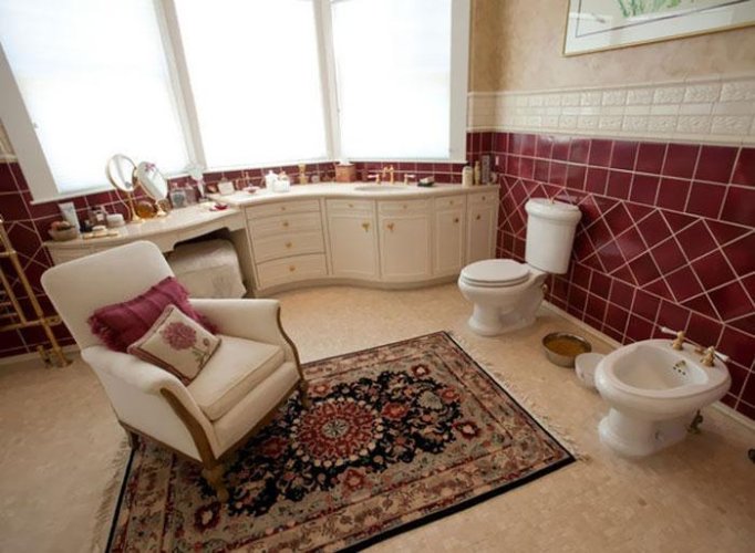 Bathroom with a throw rug, accent chair, and unusual toilets.