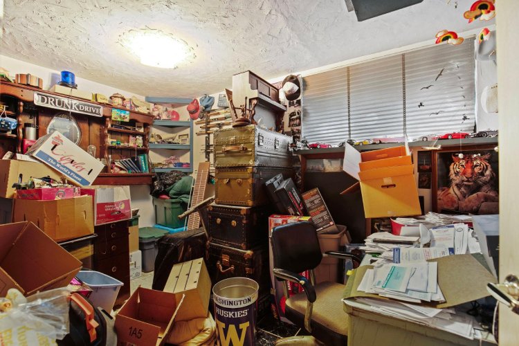 Bedroom listing photo covered with furniture , boxes, and clutter.