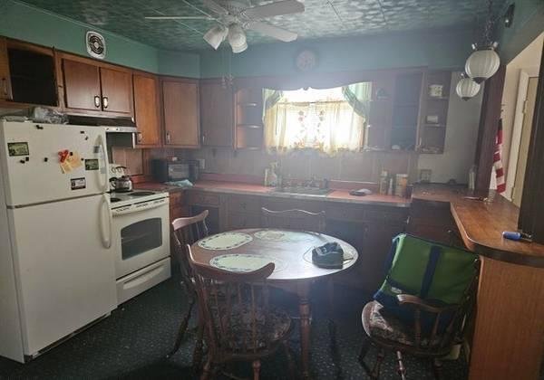 Dark photo of a kitchen with too much furniture.
