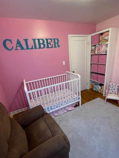 Girl's bedroom photo with pink walls and sign with the name "Caliber".