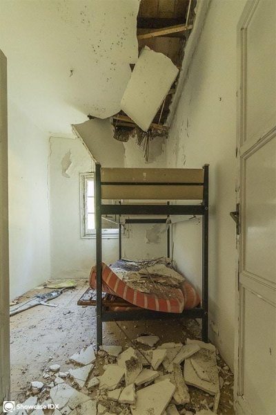 Heavily damaged bedroom with broken ceiling and walls.