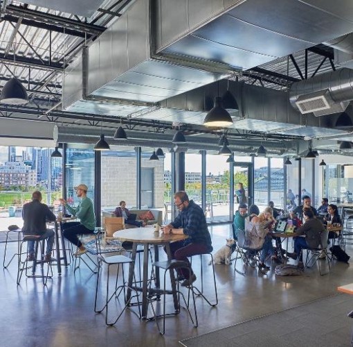 A coworking space with different groups of tables and chairs, each one occupied by professionals working alone or with other colleagues