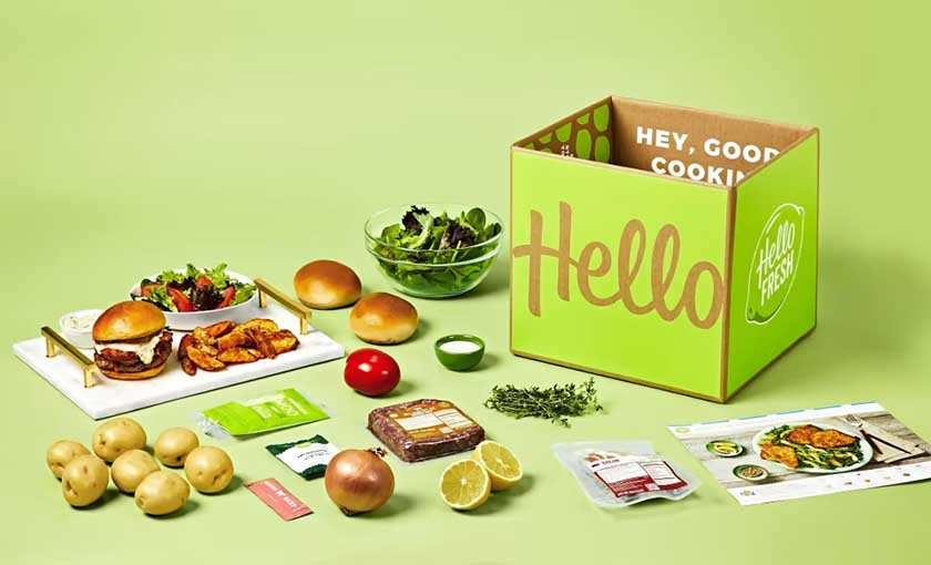 HellowFresh ad with a box, ingredients, recipe card, and a complete meal on a green background. 