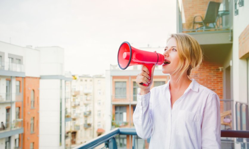 Woman on a balcony speaking into a megaphone.