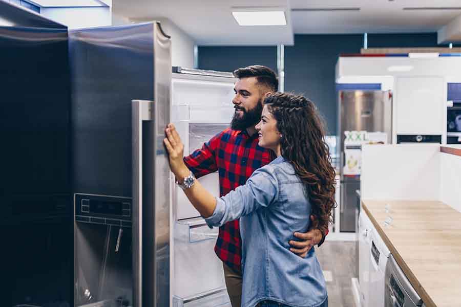 A couple choosing refrigerators in appliances store.