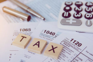Tax season with wooden alphabet blocks, calculator and pen.
