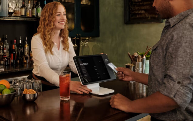 A bar customer taps to pay at a Square Stand