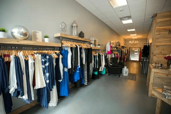 Clothing racks with blue and white clothes against grey wall in a small boutique