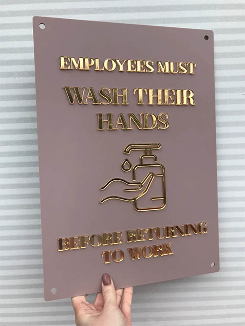 A hand holding a rose and gold employee handwashing sign.