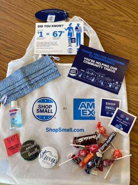Small Business Saturday swag bag with stickers candy, pins, a ticket, a mask, and more.