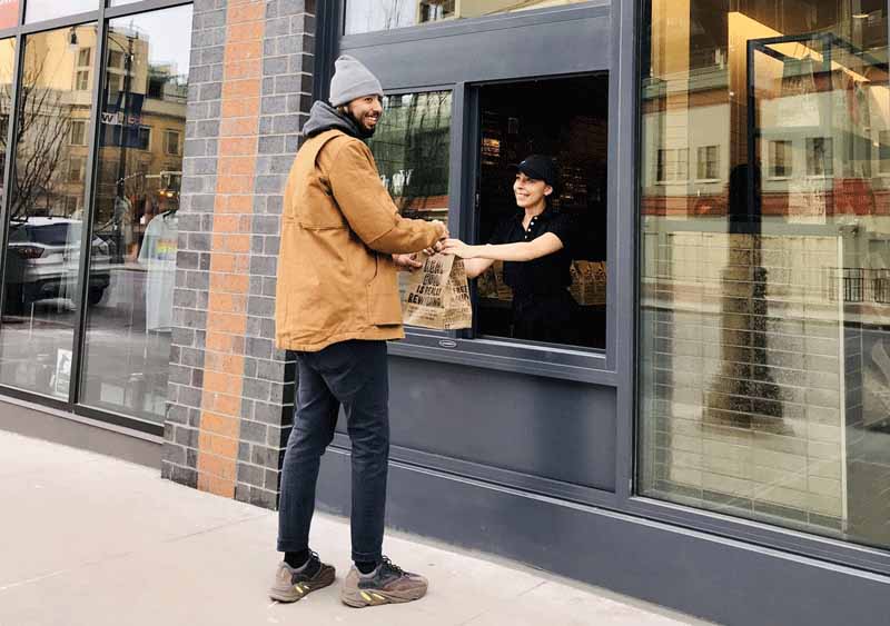 Man picking up a Chipotle order through a walk-up window.