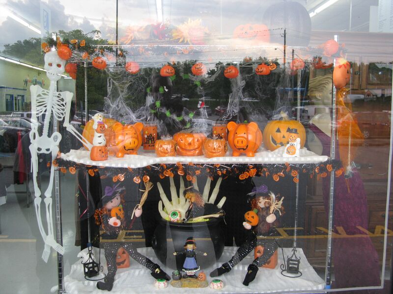 Halloween window display at a retail store pumpkins cauldron skeleton purple black orange