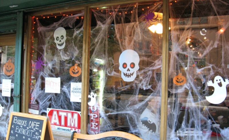 Halloween window retail display using spider webs and decal stickers of skulls ghosts and pumpkins