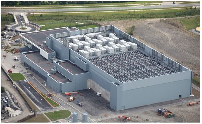 A data center operating out of a very large gray building with electrical components shown on its roof.