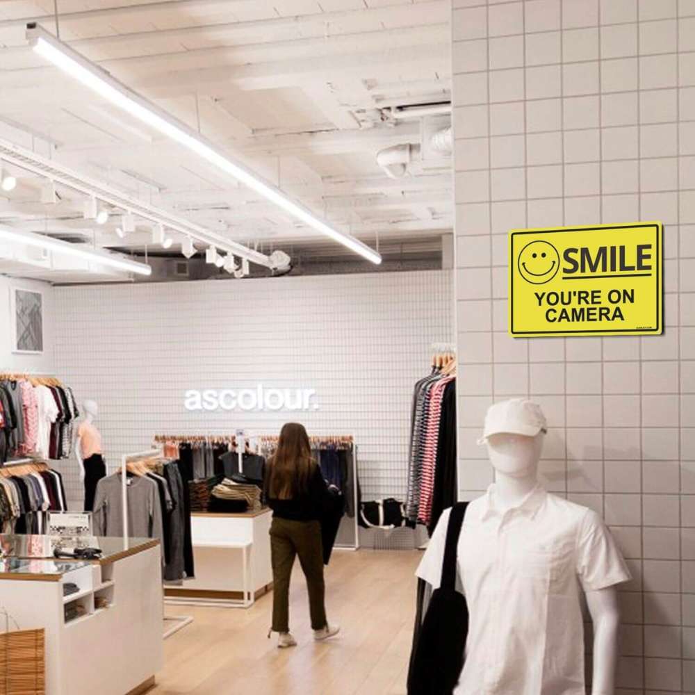 Clothing store with mannequin, shopper, and a "You're on Camera" sign on the wall. 