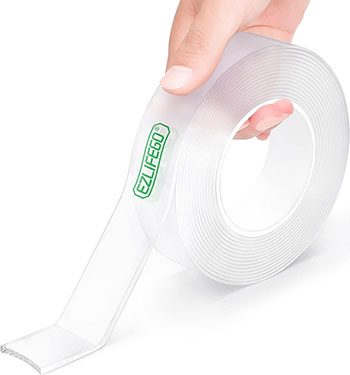 A roll of thick, clear nano tape being unrolled onto a white surface by a hand.