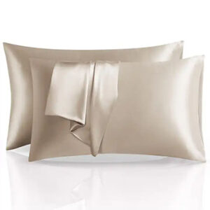 Two pillows in cream-colored, shiny silk pillowcases with an empty pillowcase draped on top.