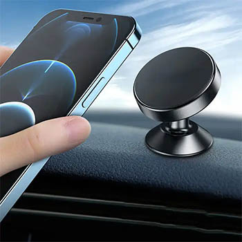 A hand placing a phone on a circular magnetic car mount attached to a car dashboard.