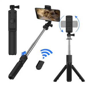 A phone attached to an extended selfie stick next to a small tripod and a remote control..
