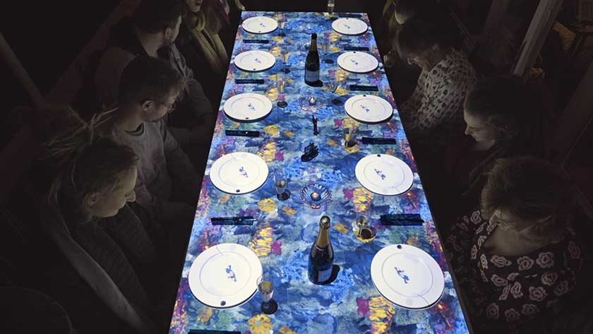 Diners seated at a dining table with projected animation.