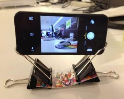 Fastening two binder clips to a strip of paper creates a simple and effective phone stand.