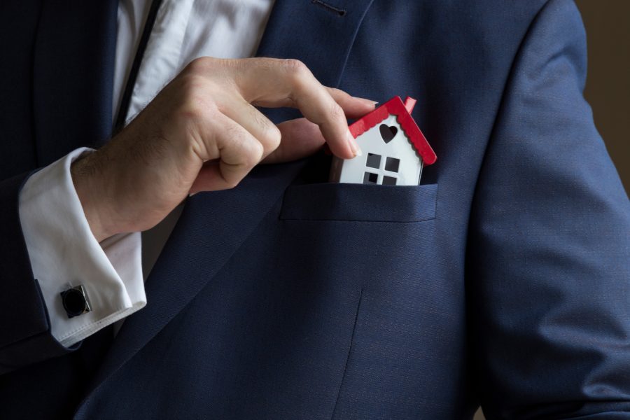 An image of a house getting tucked into a jacket lapel pocket.