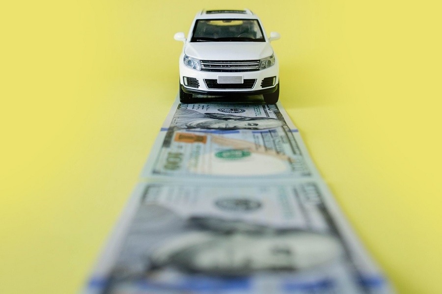 Car driving on a road made of $100 bills.