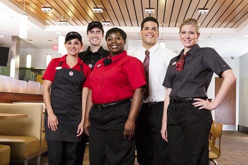 Group of people posing in different Wendy's uniforms.