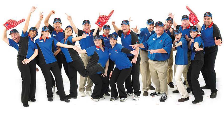 Group of people posing in Domino's dress code and aprons.