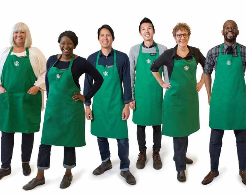 Group of people posing in Starbucks dress code and aprons.