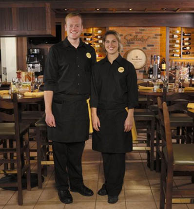 Olive Garden staff wearing black shirts, aprons, and pants as their uniform.