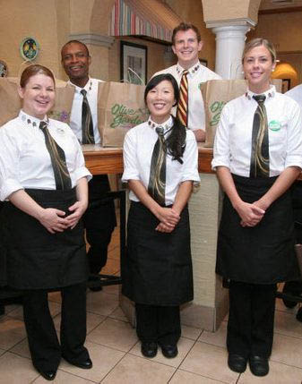 Olive Garden staff wearing long-sleeved polos, neckties, aprons, and pants as their uniform.