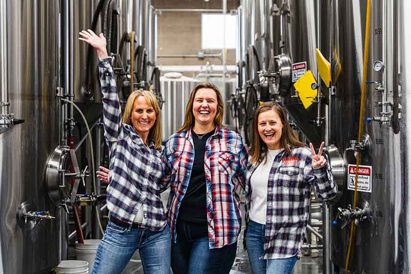 Women at a brewery wearing flannel shirts and jeans.