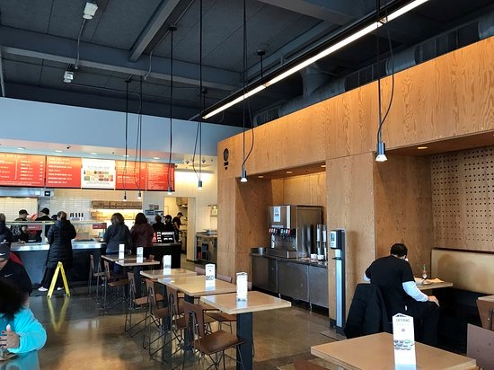 Chipotle restaurant interior with customers at the counter and tables.