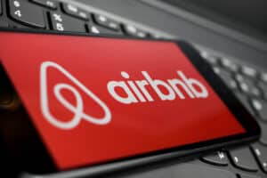 Close up of isolated mobile phone with red airbnb logo lettering on computer keyboard.