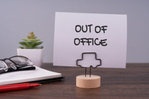 Out of office text on a paper note.