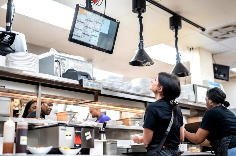 Kitchen staff looking at a screen.