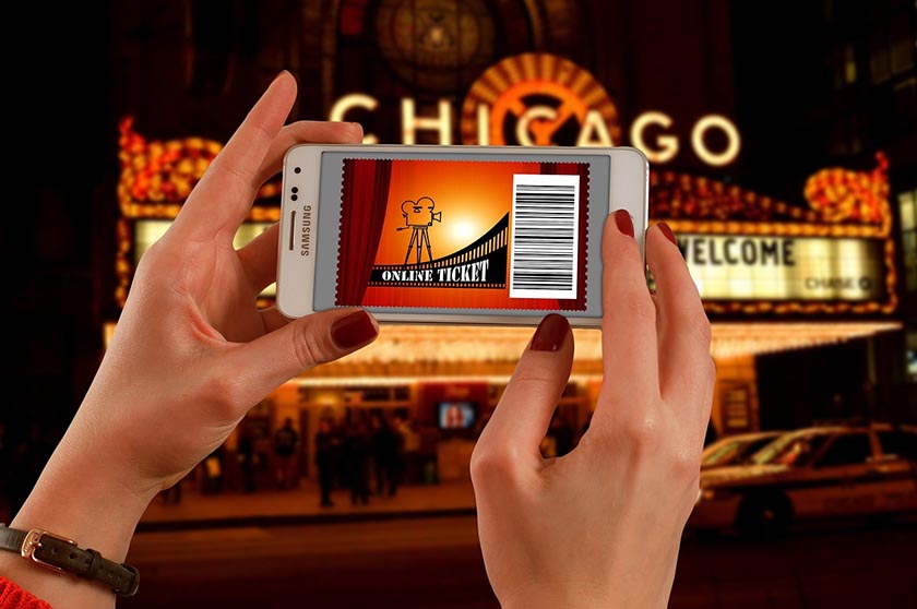 Image of a woman holding a cell phone with a theater ticket. Source: geralt on Pixabay.