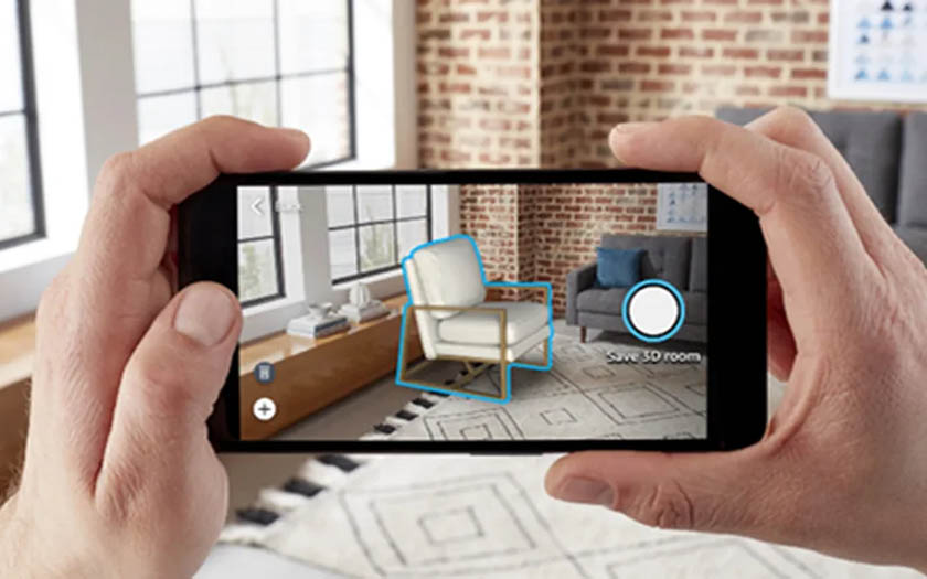 Two hands holding a smartphone in a living room with an augmented reality preview of a white chair on the screen.