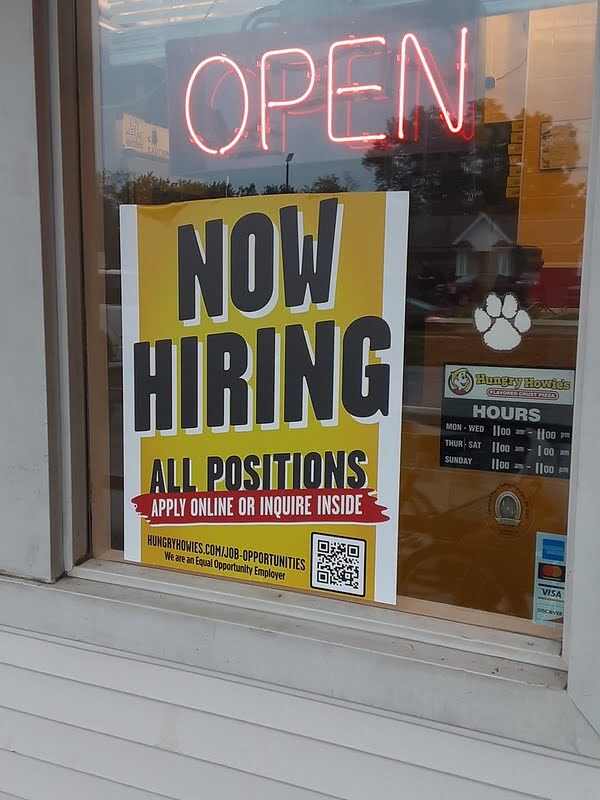 A hiring sign for Hungry Howies uses brand colors and includes a URL and QR code to its application.